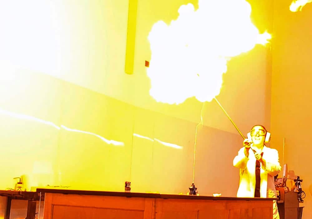 Lisa Sharpe Elles ignites a hydrogen balloon during the first day of Chemistry 130. By Doug Ward