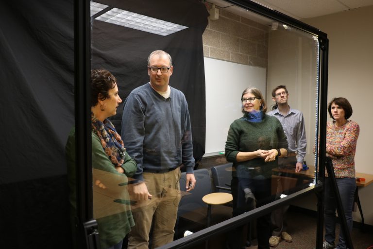 John Rinnert inside the lightboard with thre other faculty members.