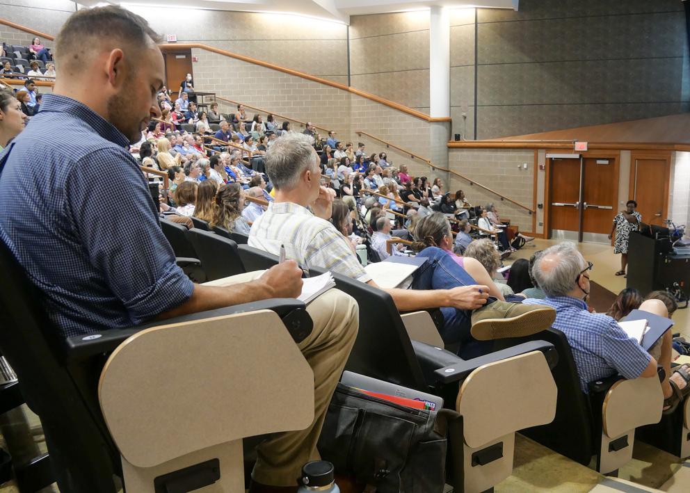 Faculty members in large lecture hall listening to keynote speaker.