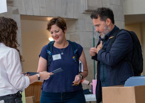 Two KU faculty members getting a folder handed to them by a grad student