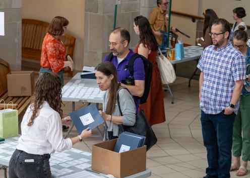 KU Faculty getting handed a folder by a grad student with others waiting in line to get folders