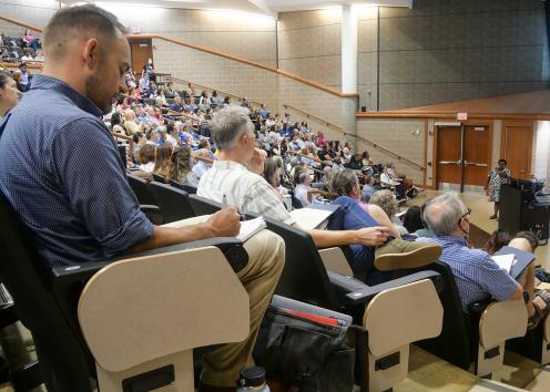 Faculty members in large lecture hall listening to keynote speaker.