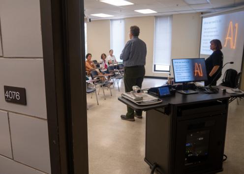 View from hallway of through door of classroom showing workshop facilitators leading a discussion.
