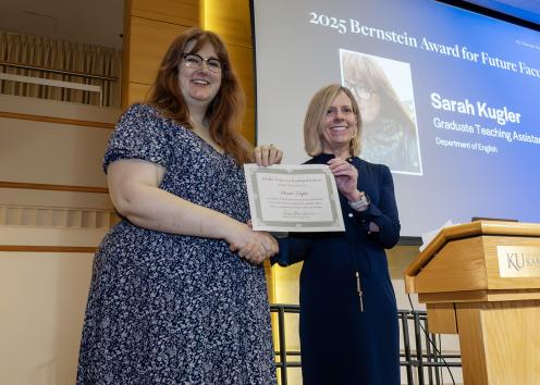 Two people on a stage shaking hands and holding a certificate