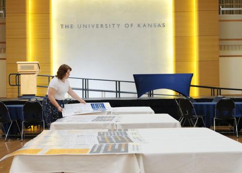 Person laying academic posters on a table in a ballroom