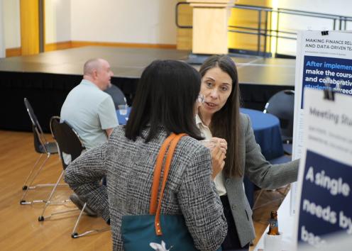 Poster presenter speaks with visitor with academic poster